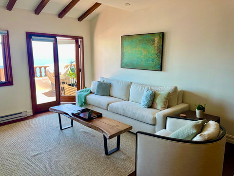 - Relax in a sun drenched living room with vaulted ceilings and soft, coastal tones
- Plush seating, a raw edge wood coffee table, and ocean inspired art set the tone
- Step outside through French doors to bask in the breeze and enjoy the view