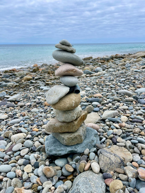 Find your balance on a peaceful shoreline where waves meet hand stacked stones.