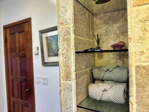 - Step into serenity with soft spa towels neatly arranged on sleek glass shelves
- Fragrant reed diffuser and coastal décor set a soothing, elegant tone
- Earthy stone textures and warm wood accents invite you to unwind in style