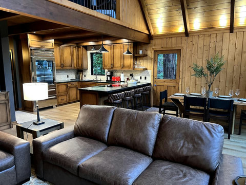- Cozy leather seating while admiring the open plan layout & vaulted wood ceilings
- Gourmet kitchen featuring essential appliances and bar seating for four
- Share memorable meals at the elegant dining table set for six with forest views all around