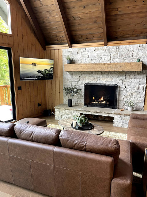 - Unwind by the striking stone fireplace beneath rustic beams and a cathedral ceiling
- Stream your favorites on the wall mounted smart TV, visible from every seat
- Soak in forest views through large sliding doors that lead to a private deck