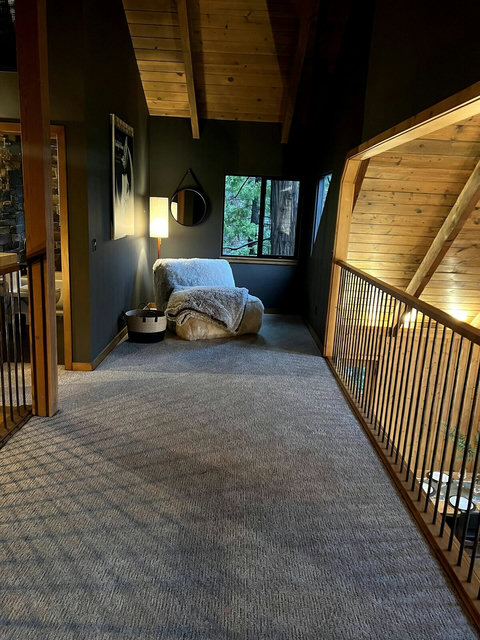 - Escape upstairs to a peaceful loft space with plush seating & cozy throws
- Enjoy a good book or morning coffee while gazing out to the treetops through large windows
- Sloped wooden ceilings & soft lighting create a tranquil, cabin inspired corner