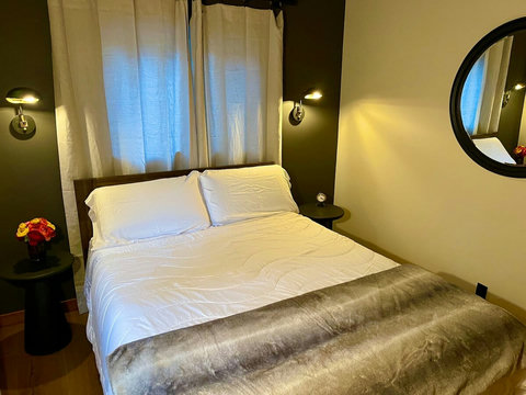 - Sleep peacefully in a plush queen bed with crisp linens and a cozy fur textured throw
- Enjoy ambient lighting and minimalist décor, with convenient bedside shelves
- Elegant touches like a round mirror and fresh blooms add warmth and style