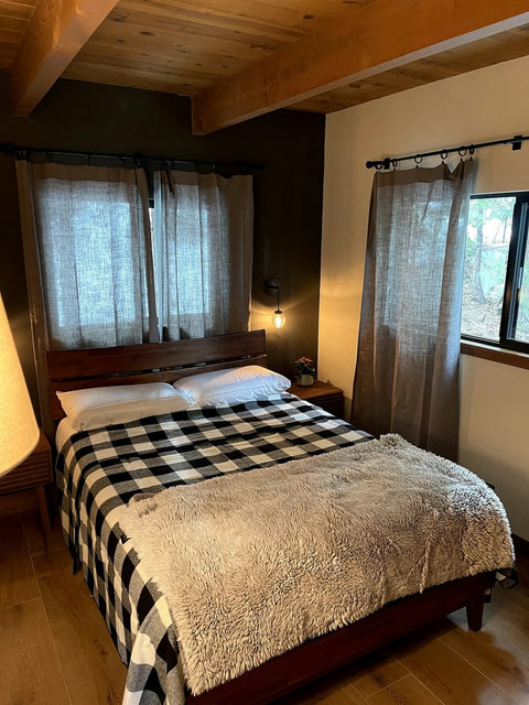 - Wake up to forest views through dual windows wrapped in soft linen curtains
- Sleep soundly on a comfy queen bed with layered blankets and wooden bed frame
- Beamed ceilings and earthy tones enhance the serene, cabin style ambiance