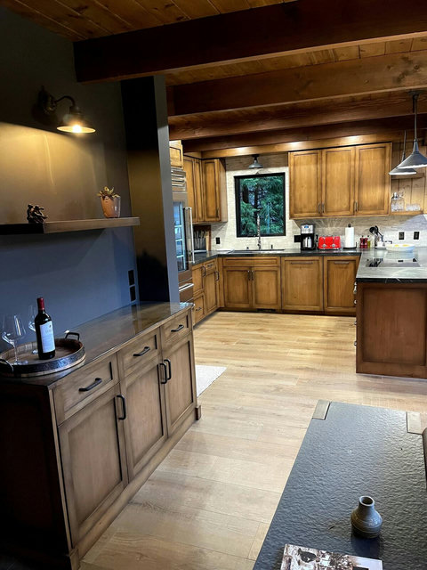 - Rustic charm with rich wood cabinetry, exposed beams, & soft ambient lighting
- Serene forest views through the kitchen window as you prepare your favorite meals
- Unwind with a bottle of wine at the welcoming bar corner, perfect for evening indulg