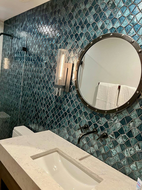 - Stunning sapphire toned tile backsplash adds a bold, stylish touch to this spa bath
- Industrial style mirror and lighting bring contrast to the sleek quartz vanity
- Matte black wall mounted fixtures complete the modern, exclusive look