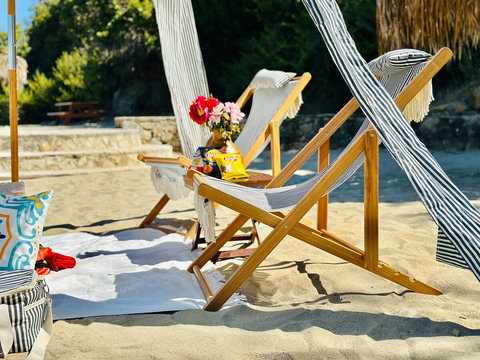 Kick back on striped loungers with snacks and flowers under a breezy cabana on soft beach sands.