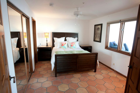 - Rest easy in a queen bed with crisp white linens & bright floral accent pillows
- Earth toned tile floors & dark wood furniture create a calm, grounded atmosphere
- Enjoy morning light streaming through the large window beside a cozy reading nook

