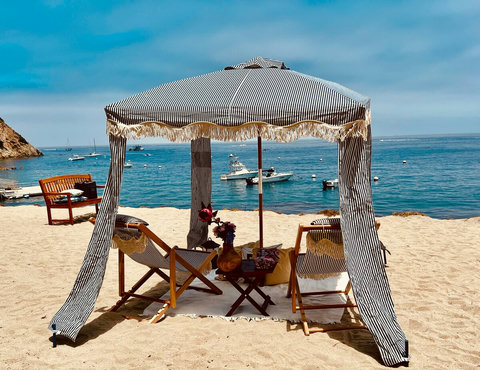 Relax under a striped beach cabana with cozy chairs and oceanfront serenity just steps from the surf.