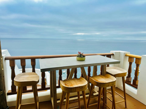 - Enjoy serene ocean panoramas from this stylish balcony dining nook
- Elegant concrete top table paired with natural wood stools invites alfresco meals
- Succulent centerpiece adds a charming, coastal touch to the peaceful setting

