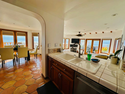 - Cook with a view in this open kitchen overlooking the ocean & sunlit living area
- Classic tiled countertops, wood cabinetry & arched details blend charm & function
- Seamless layout connects kitchen, dining & patio for the ultimate entertaining sp