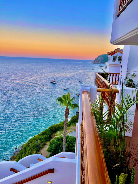 - Watch vibrant sunsets melt into the horizon from your private oceanfront balcony
- Gaze at a tranquil coastline dotted with boats, lush palms, and coastal cliffs
- Morning coffee or evening wine, this balcony view is pure vacation bliss