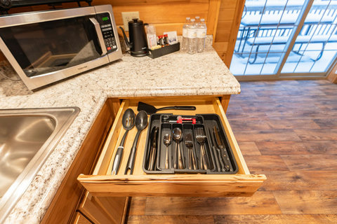 well-organized kitchen drawer with utensils and a microwave on granite countertops