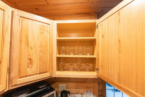 Open wooden kitchen cabinet with glassware neatly arranged on shelves