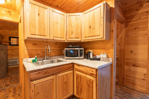 Compact kitchen corner with wooden cabinetry, a stainless steel sink, and essential appliances.