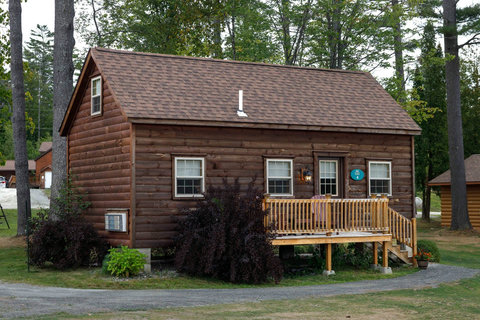 Cozy rustic cabin with a wooden deck surrounded by trees.