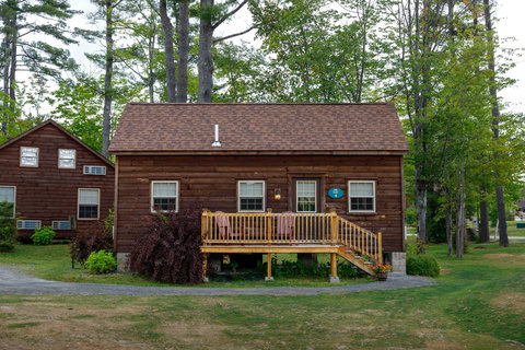 Rustic cabin with a wooden deck surrounded by trees in a peaceful setting