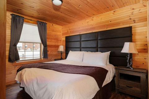 Cozy bedroom with wood-paneled walls and a large window for natural light