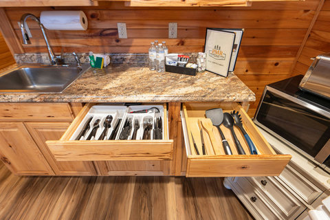 rustic kitchen drawers stocked with utensils and a granite countertop with a sink