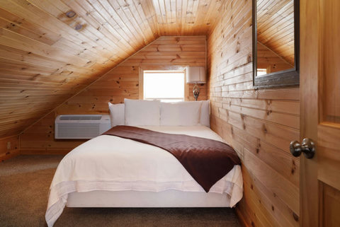 Cozy attic bedroom with wood-paneled walls and a comfortable bed.