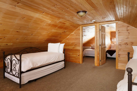Cozy attic bedroom with wood-paneled walls and twin beds for a rustic retreat.
