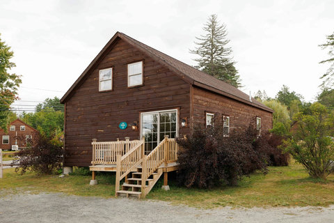 Rustic cabin with a wooden deck surrounded by greenery.