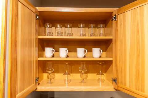 Organized wooden cabinet with glassware and mugs for convenient use.