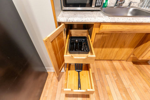 Organized wooden kitchen drawers with utensils and a spatula for convenient cooking.
