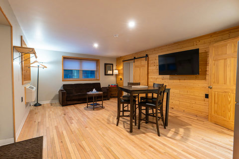 Cozy living area with wood-paneled walls, a dining table, and a wall-mounted television.