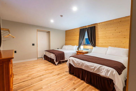 Spacious room with two queen beds and a wood-paneled accent wall