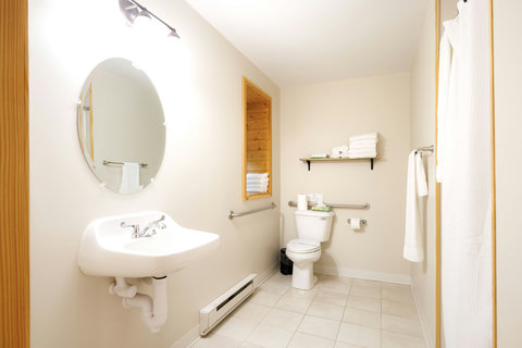 Bright and accessible bathroom with a wall-mounted sink and stocked towels.