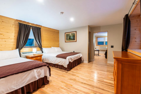Spacious rustic bedroom with two queen beds and hardwood floors.