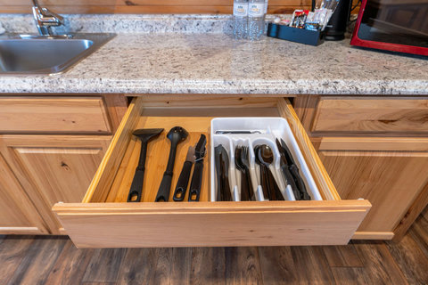 Organized kitchen drawer with utensils and granite countertop in a rustic-style kitchen.