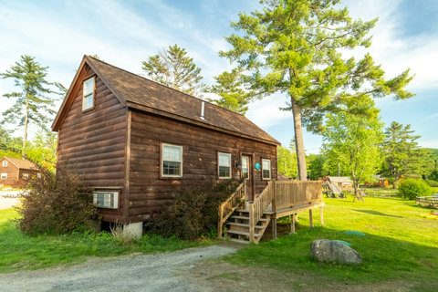 Rustic wooden cabin with a spacious deck surrounded by greenery.