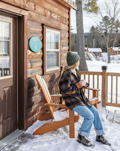 Relax on the rustic cabin porch while enjoying snowy mountain views.