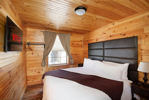 Cozy bedroom with wood-paneled walls and a large bed featuring a leather headboard.