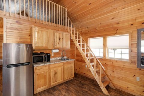 Compact kitchen area with wooden cabinetry and a staircase leading to a loft space.