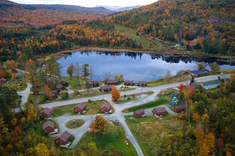Rustic cabins nestled by a serene lake surrounded by vibrant autumn foliage.