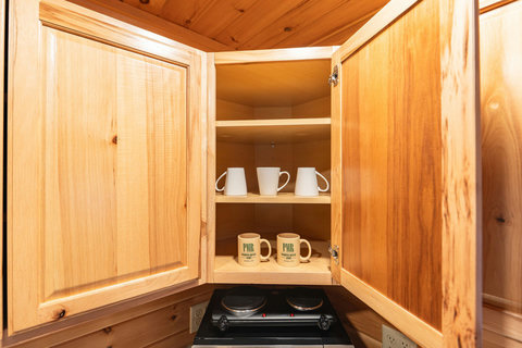 Corner kitchen cabinet with mugs and a two-burner electric stove below