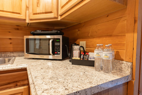 Compact kitchen corner with microwave, kettle, and complimentary bottled water on granite countertop