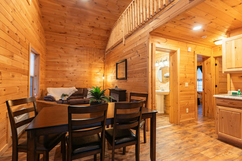 Cozy rustic dining and living area with wood-paneled walls and vaulted ceilings.