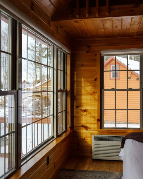 Cozy cabin interior with large windows offering snowy outdoor views.