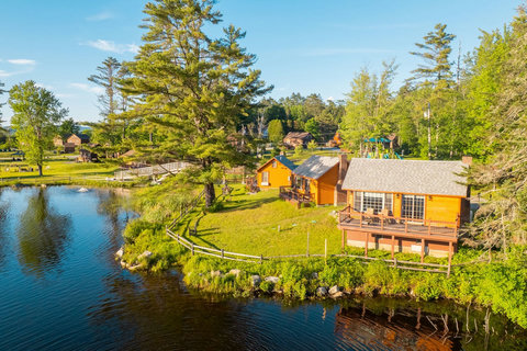 Rustic lakeside cabins with private decks overlooking the water and surrounding greenery.