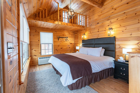 Cozy bedroom with wood-paneled walls and a loft area for extra space.