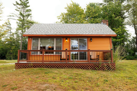 Cozy log cabin with a front porch surrounded by trees.