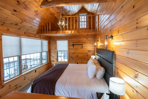 Cozy rustic bedroom with large windows and loft space