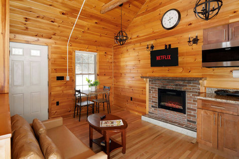 Cozy cabin living area with a brick fireplace and mounted television for relaxing entertainment.