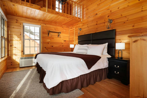 Cozy bedroom with wood-paneled walls and natural light from large windows