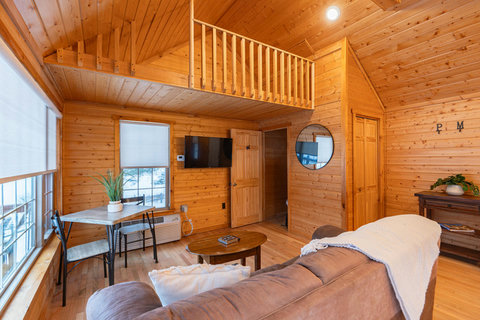 Cozy living area with wood-paneled walls and a loft space above.