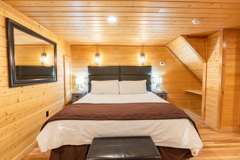 Cozy bedroom with wood-paneled walls and a king-size bed for a restful stay.